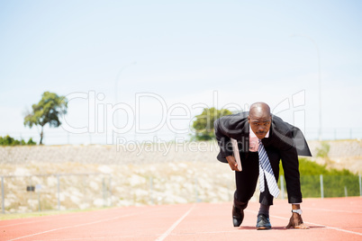 Businessman with laptop ready to run