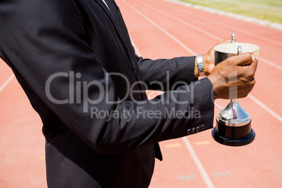 Mid section of businessman holding winning trophy