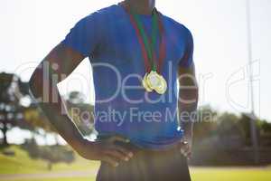 Mid section of athlete posing with gold medal after victory