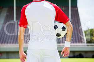 Mid section of football player standing with a ball