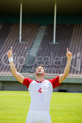 Excited football player with hands raised
