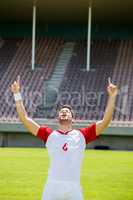 Excited football player with hands raised