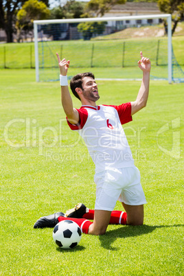 Excited football player kneeling in stadium