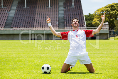 Excited football player kneeling in stadium