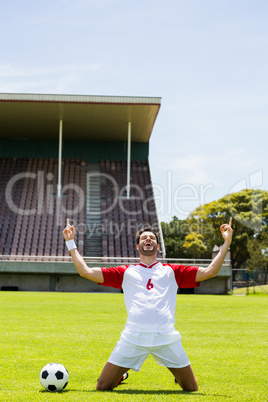 Excited football player kneeling in stadium