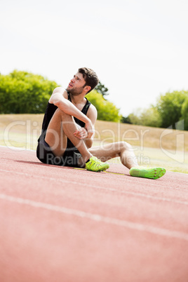 Tired athlete sitting on the running track