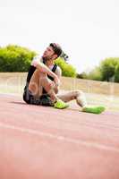 Tired athlete sitting on the running track