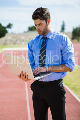 Businessman using a laptop on the running track