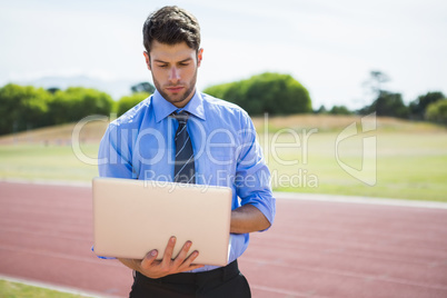 Businessman using a laptop on the running track