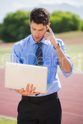 Businessman using a laptop on the running track