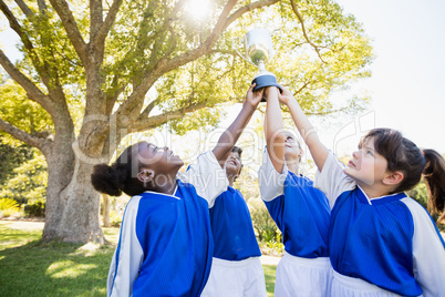 close up view of children soccer team arms in the air with cup