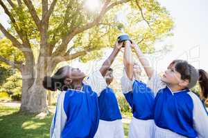 close up view of children soccer team arms in the air with cup