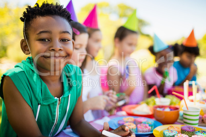 Close up of cute boy smiling in front of other children during a