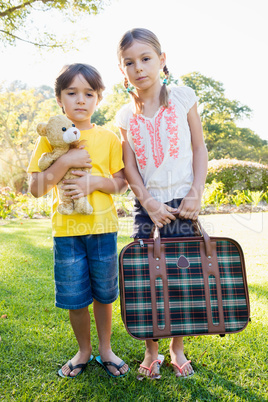Portrait of cute brother and sister posing with old luggage and