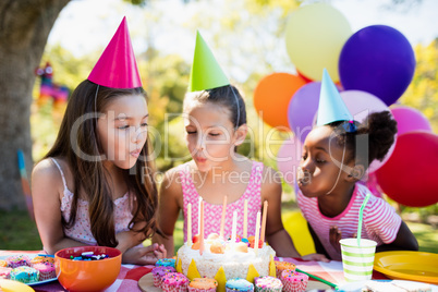 Portrait of cute girls blowing on candle during a birthday party