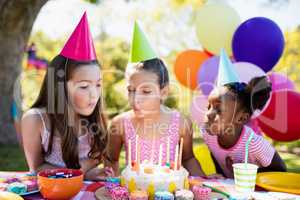 Portrait of cute girls blowing on candle during a birthday party
