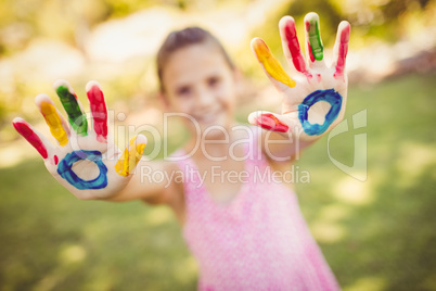 Little girl showing her painted hands to the camera in a park