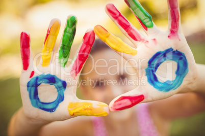 Little girl making a triangle with her painted hands to the came