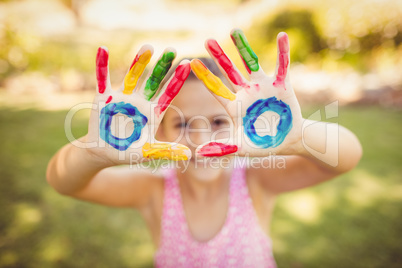 Little girl making a triangle with her painted hands to the came