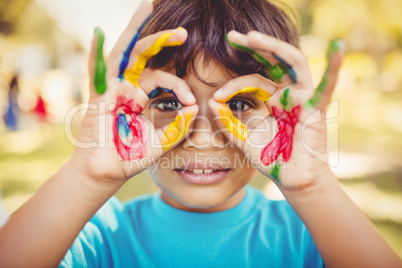 Little boy making glasses with his painted hands
