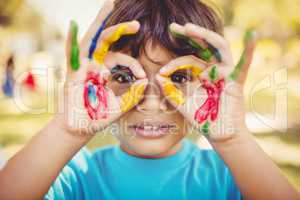 Little boy making glasses with his painted hands