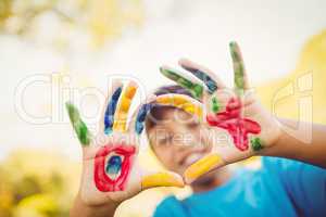 Boy making a circle to the camera with his hands painted