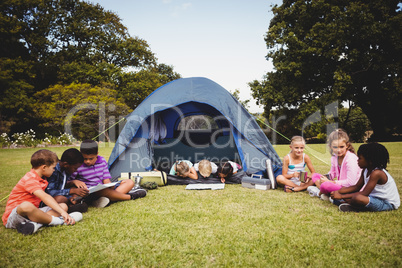 Smiling kids lying and reading in the tent together