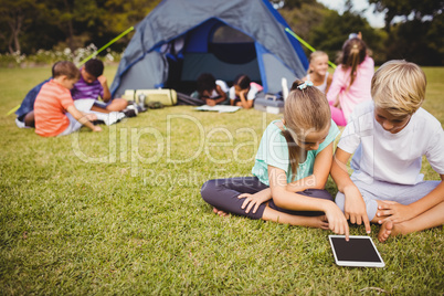 Smiling children are looking their tablet with other children be