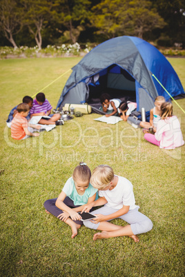 Smiling children are looking their tablet with other children be