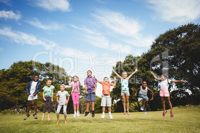 Smiling kids jumping together during a sunny day