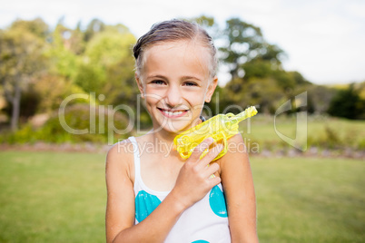 Kid posing at camera during a sunny day with her water gun