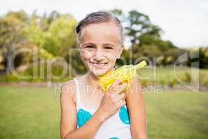 Kid posing at camera during a sunny day with her water gun