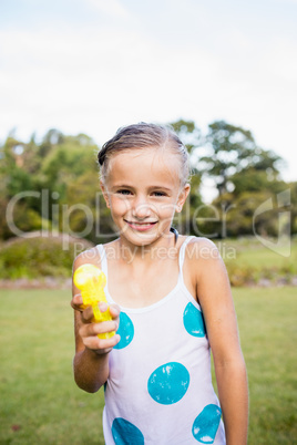 Kid posing at camera during a sunny day with her water gun