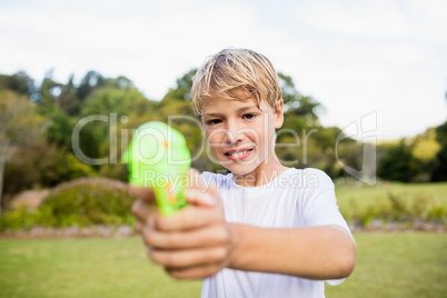 Kid posing at camera during a sunny day with his water gun