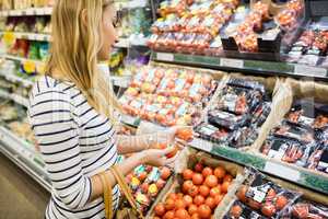 Thoughtful woman taking products on shelf