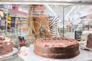 Happy woman looking at desserts with hands in front of mouth