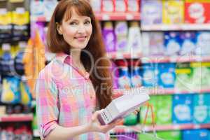 Portrait of woman with shopping basket holding product