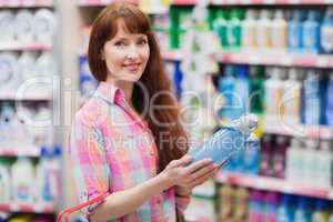 Beautiful woman posing with detergent and shopping basket