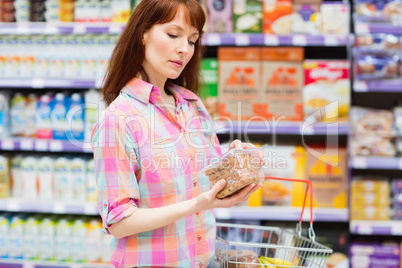 Concentrated woman choosing carefully a product