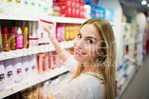 Smiling blonde woman posing while picking a product