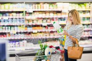 Customer at supermarket with a bottle in hands