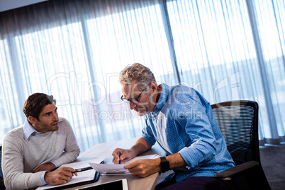 Two businessmen reading a document and interacting