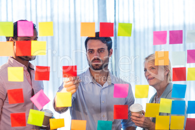 Business people looking at post it on the wall