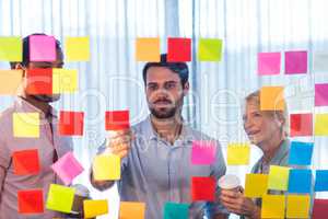 Business people looking at post it on the wall