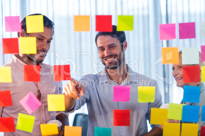 Business people looking at post it on the wall