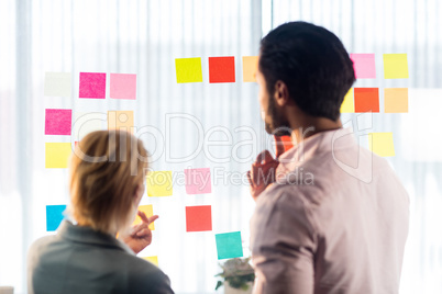 Rear view of two business people looking at post it wall