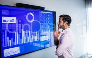 Side view of serious man looking at graph on a screen