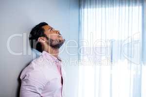 Businessman standing against wall and looking up