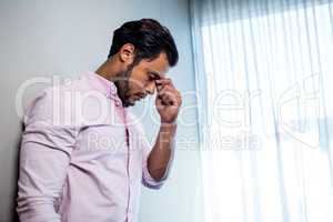 Exhausted man standing against the wall and looking down