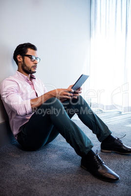 Serious businessman using tablet computer while sitting on the f